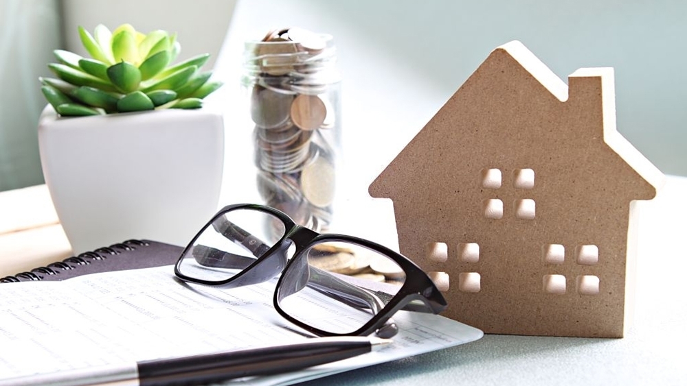 Wood house model ,coins, eyeglasses and financial statement