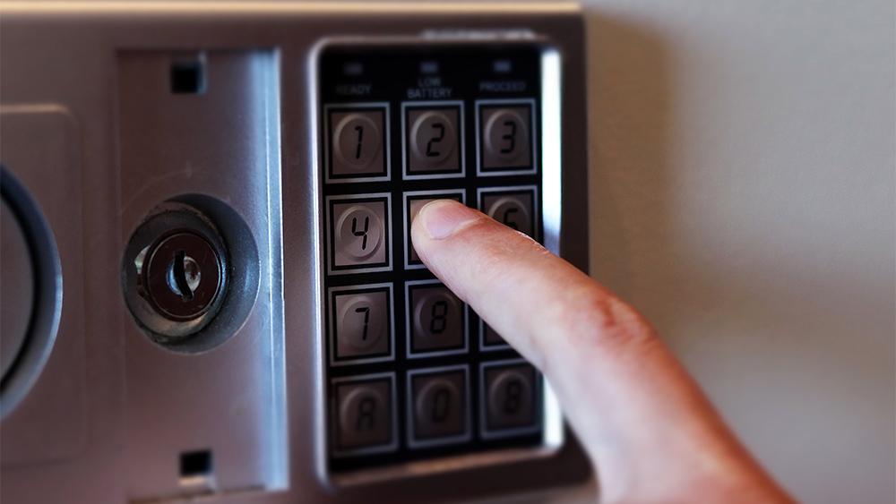 Safe box with keypad and a hand touching keys