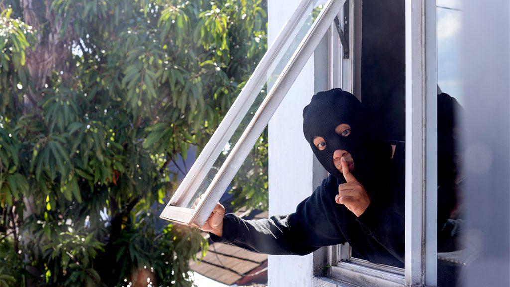 Thief burglar opening window trying to escape