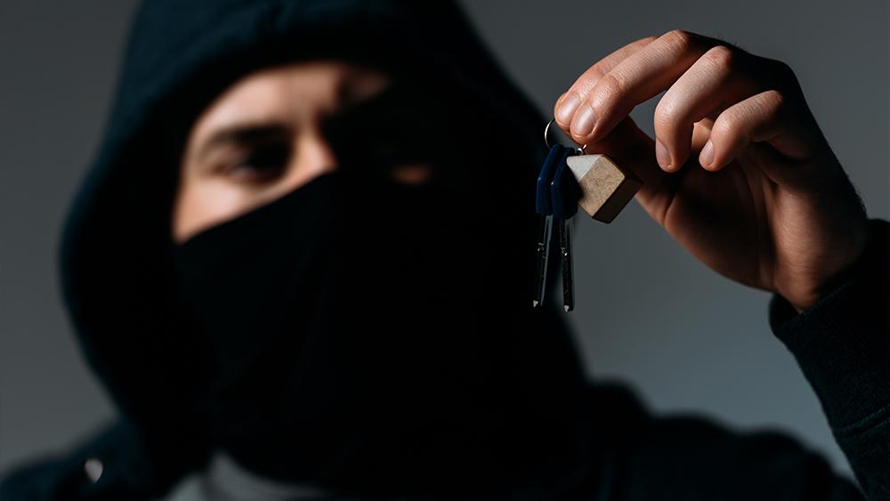 Thief in mask and black hoodie looking at keys